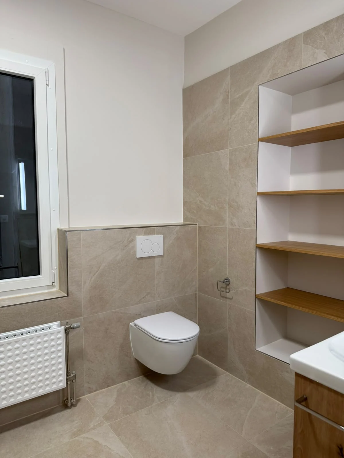 WC suspendu, fenêtre et rangements.