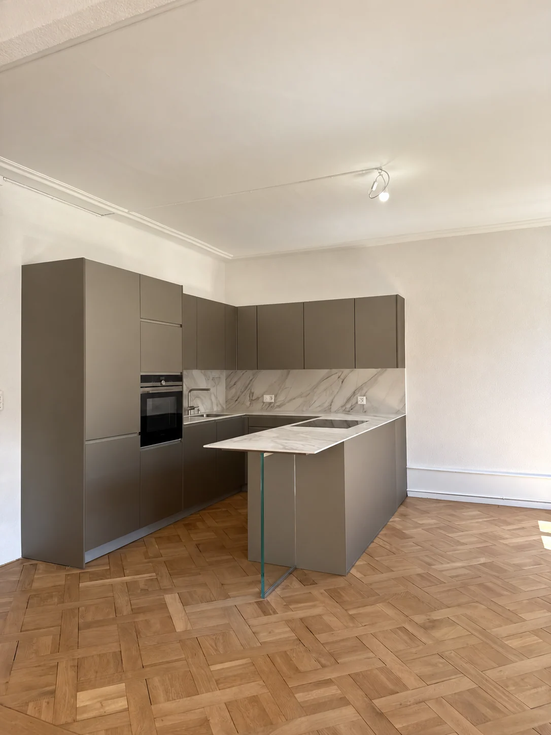 Cuisine équipée et parquet en damier.